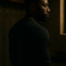 Portrait cinématographique d’un homme afro-américain seul, en semi-profil, dans un vestiaire vide, illustrant les silences et sacrifices derrière les trajectoires de réussite.